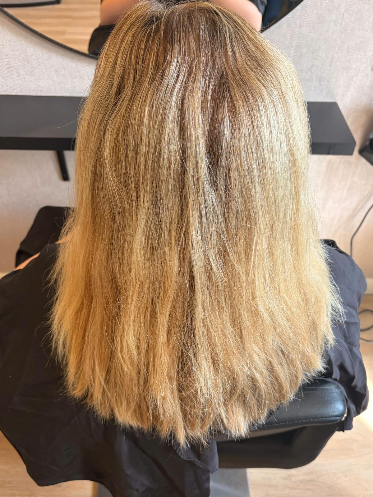 Lang blond haar op de kappersstoel, van achteren gezien