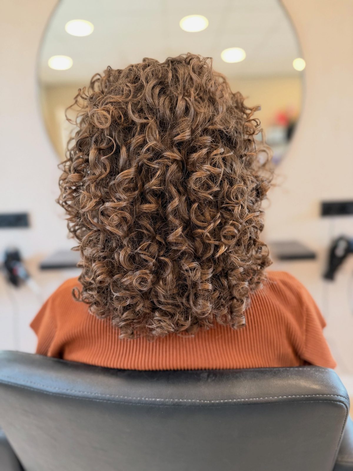 Volle bruine krullen na een curls cut, voor de ronde spiegel